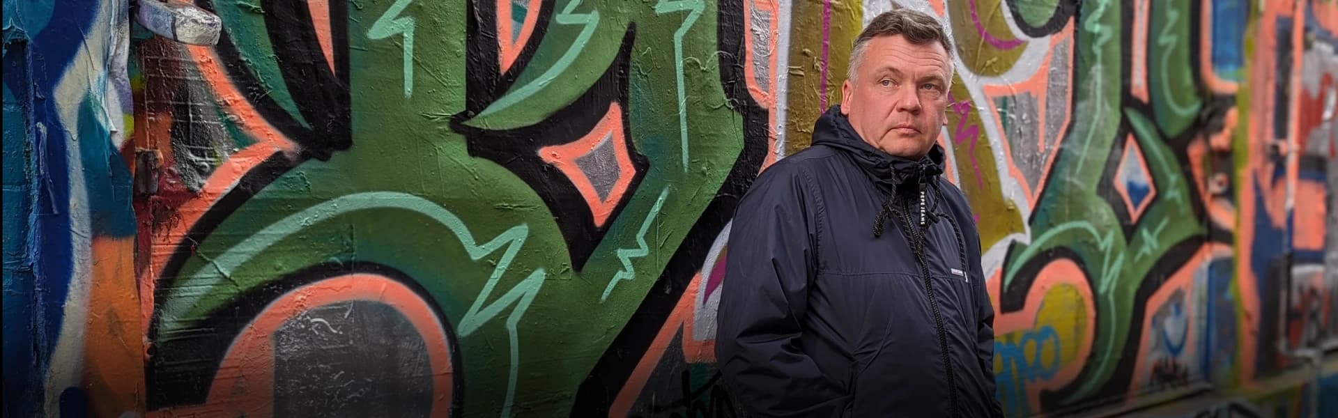 Paul Billington against a wall of graffiti